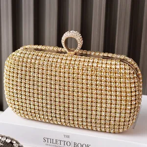 Elegante pochette da sera dorata con strass e chiusura ad anello scintillante su un libro