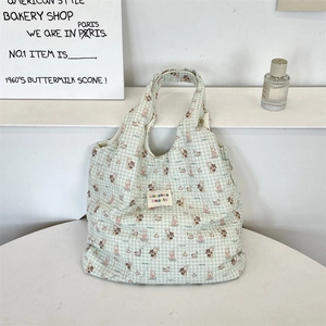 Close-up of green checkered tote bag fabric with cartoon animal prints and woven label