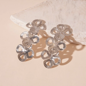 Detailed close-up of silver triple-flower drop earrings with engraved metallic texture