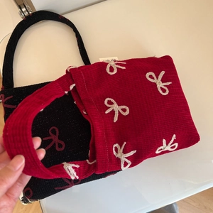 Détail de sacs cabas en tweed rouge et noir avec broderie nœud et fermeture magnétique