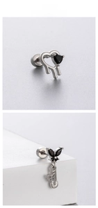 Macro view of gothic spider heart and butterfly safety pin earrings with black zircons