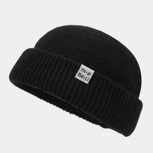 Detailed knit texture of a black vintage docker hat with white logo label on cuff