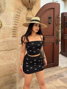 Sexy black two-piece set featuring bow print tube top and bodycon mini skirt for women