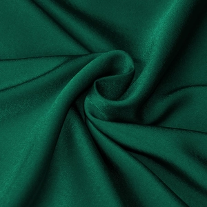Detail of green satin fabric showing elegant silk texture and soft glowing drapes