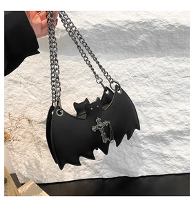 Close-up of black bat-shaped gothic crossbody bag with silver chain and cross pendant