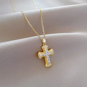 Luxurious gold cross necklace with shimmering zircon stones on soft beige silk background