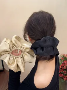 Detail of satin scrunchies with floral jacquard texture in black and champagne colors