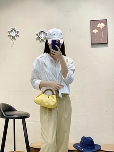 Yellow ruched cloud bag featuring dark wooden handle and fine metal chain detail