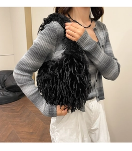 Detailed texture of black faux fur shoulder bag worn by model in a cozy interior setting