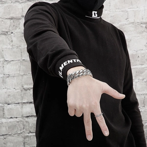 Détail d'un bracelet gourmette argenté poli et d'une bague corde sur la main d'un mannequin