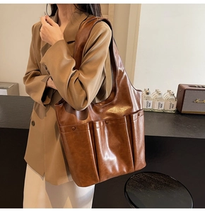 Brown leather tote bag featuring a large external pocket and spacious casual design