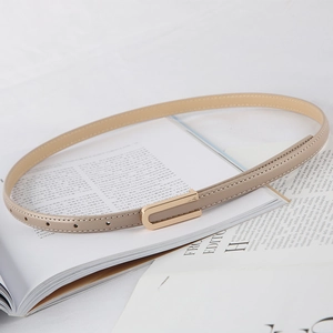 Cintura sottile da donna in pelle beige con fibbia a U dorata su una rivista di moda