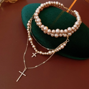 Detail of layered gold necklaces with champagne pearls and crystal cross pendants