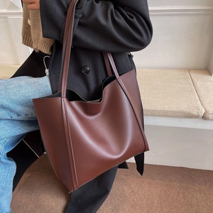 Minimalist large capacity dark brown leather tote bag shown on model with shoulder strap
