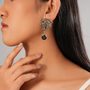 Dark aesthetic flower earrings with black crystals and gold metal on female model