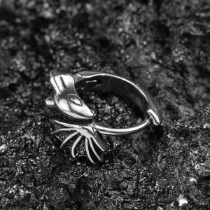 Gothic silver dragon and wing stud earrings on black volcanic rock background