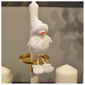 Detail of plush snowman ornament with carrot nose hanging on a white festive candle
