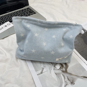 Close-up of denim cosmetic bag with white star patterns and brand label on fabric