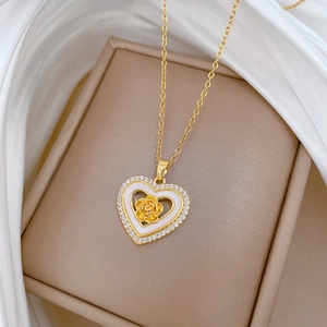 Close-up of golden rose heart pendant with zircons resting on a luxury gift box