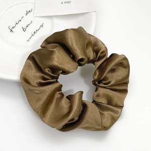 Deep bronze satin silk scrunchie with glossy texture on elegant white tray background
