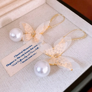Detailed close-up of elegant lace butterfly earrings with white pearls and diamonds