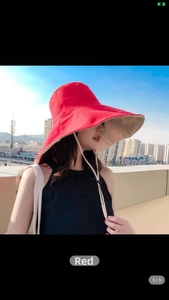 Detail of red and beige wide brim sun hat with adjustable drawstring and foldable canvas