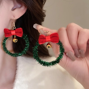 Christmas wreath earrings with red velvet bow and gold bell hanging on green plush