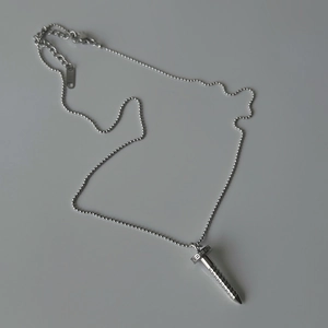 Close-up of minimalist silver nail pendant necklace with zircon on grey background