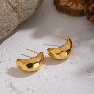 Gros plan de boucles d'oreilles dorées avec texture martelée sur fond blanc texturé