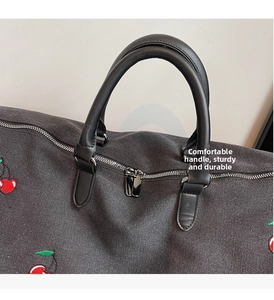 Detail of comfortable leather handles and cherry embroidery on large canvas travel tote