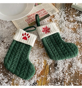 Detail of green knit Christmas stockings with red embroidered paw and snowflake patterns