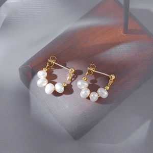 Detailed view of elegant baroque pearl earrings with golden metal setting on soft mesh