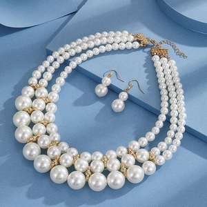 Detailed view of triple-layer pearl necklace and matching earrings on blue background