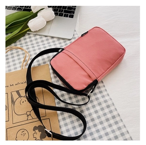 Pink corduroy crossbody bag with adjustable strap and front zipper pocket detail