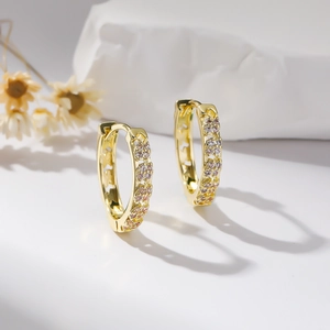 Gold hoop earrings featuring hollow floral patterns and inlaid purple zircon stones