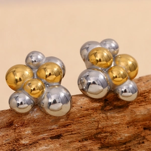 Vue macro de boucles d'oreilles bicolores en grappe de perles sur support en bois