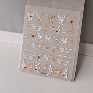 Macro shot of gold butterfly nail decals with red rhinestones and English quotes
