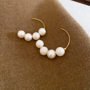 Detail of vintage French gold C-shape earrings with textured pearl finish on wool