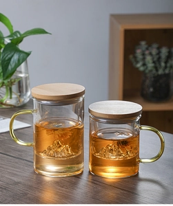 Detailed view of glass tea cups with wooden lids and internal mountain design for loose tea