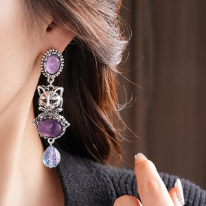 Detailed view of vintage cat earrings with purple gemstones and metallic finish