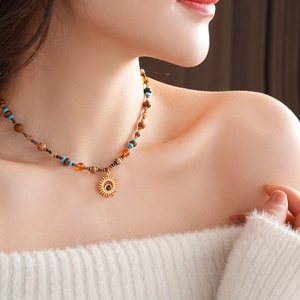 Close-up of golden sun pendant necklace with natural beads on female model