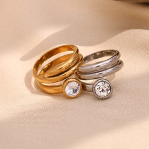 Detail of 18K gold and silver snake head rings with round white diamonds on fabric