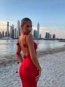 Elegant red backless maxi dress with 3D floral details on the straps at sunset beach