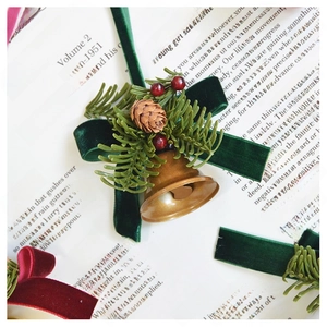 Close-up of vintage bronze bell with green velvet bow, pine cones and red berries decor