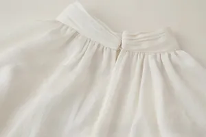 Detail view of cream ruffle high neck blouse with elegant pleats and back button closure