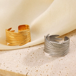Adjustable 18K gold and silver stainless steel feather rings on beige stone background