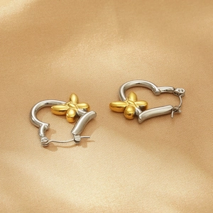 Detail of silver and gold heart butterfly earrings on glossy champagne satin background