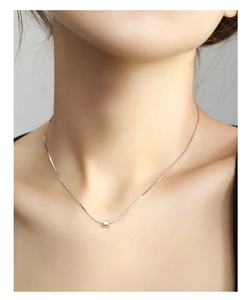 Close-up of minimalist silver cube pendant on a fine snake chain necklace for women