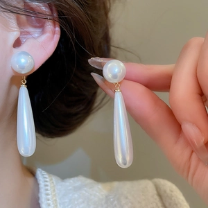Elegant drop earrings featuring long white pearls and gold hardware worn by a model