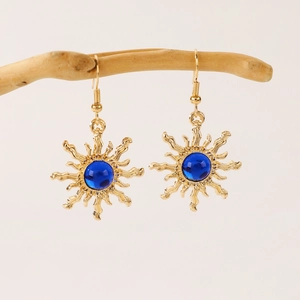 Bohemian gold sunburst earrings with centered blue gemstone hanging on a branch